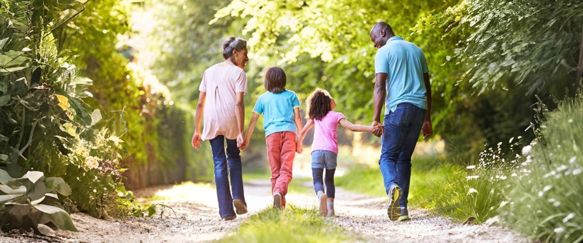 Family walking hand in hand on a sunny trail